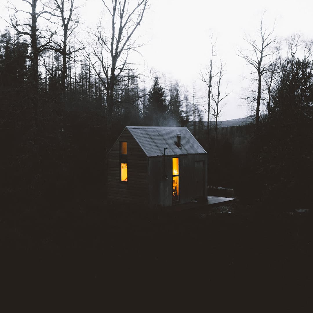 A bothy with a lit window, in the Cairngorms